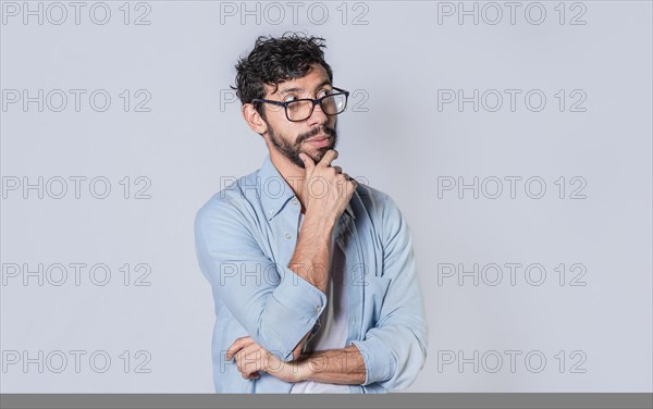 Young man wondering with his hand on his chin on an isolated background