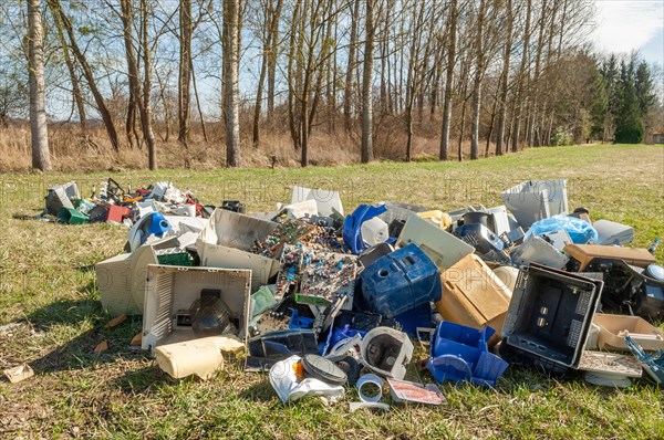 Polluting plastic waste and computer scrap illegally disposed of in a meadow