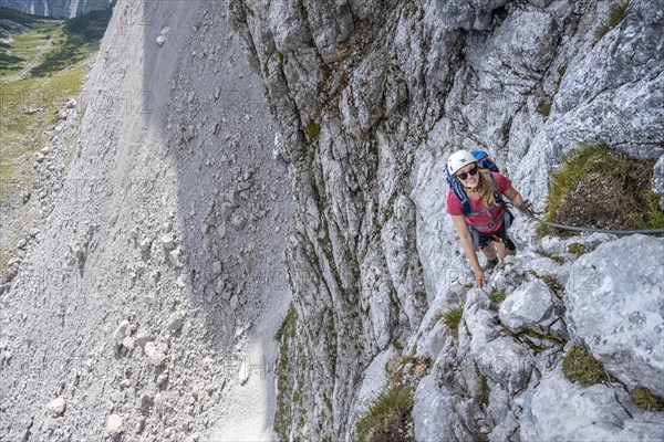 Young woman climbing a steep rock face