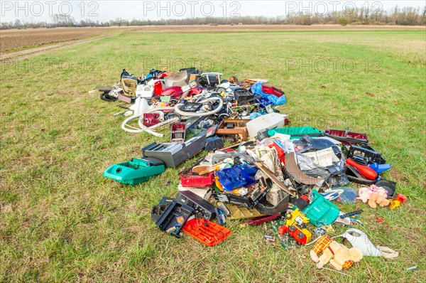 Polluting plastic waste and computer scrap illegally disposed of in a meadow