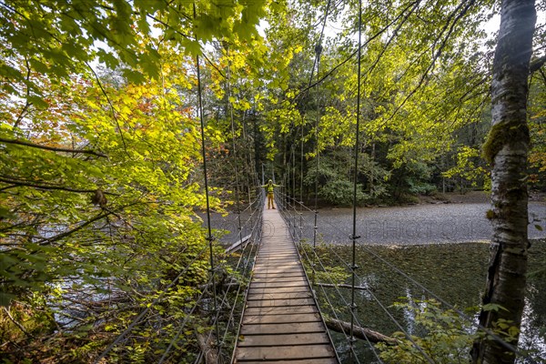 Hikers on suspension bridge in autumnal forest