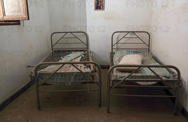 Two metal bedsteads in narrow room