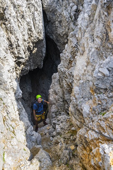 Young man climbing out of a rock hole