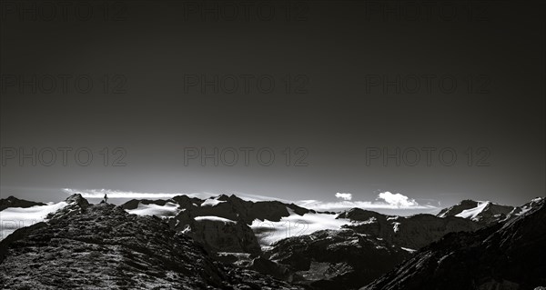 Climber on rocky outcrop with South Tyrolean mountains at blue hour