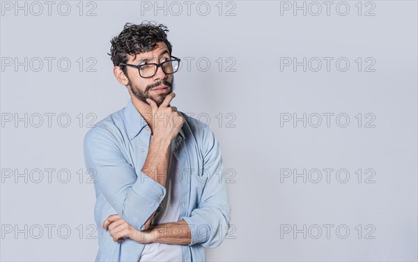 Young man wondering with his hand on his chin on an isolated background