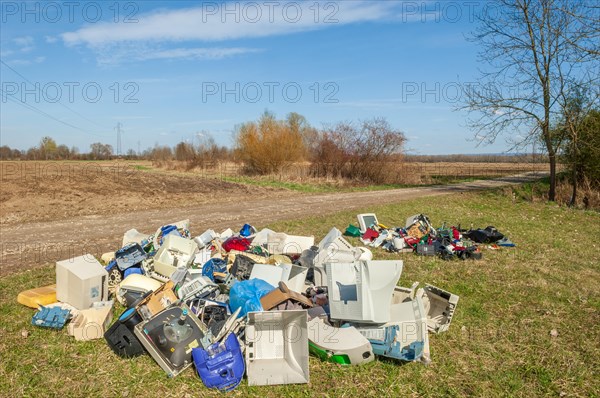 Polluting plastic waste and computer scrap illegally disposed of in a meadow