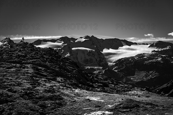 Climber on rocky outcrop with South Tyrolean mountains at blue hour