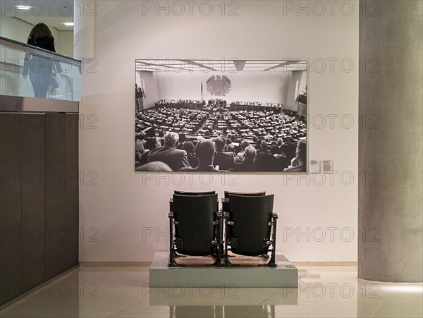 Historic row of chairs of the plenary hall standing in front of an old photo in the German Reichstag