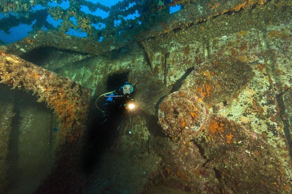 Diver looks at illuminated replacement propeller on deck of wreck of sunken cargo ship M/V M/N Kent