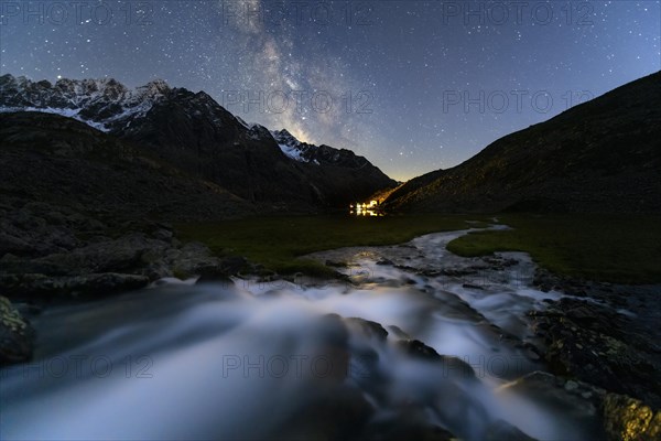 Mountain stream with Winnebachsee hut and Winnebach peaks with starry sky and Milky Way