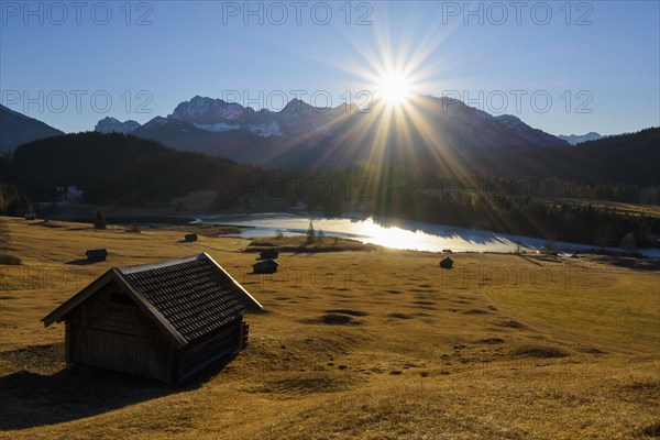 Sunrise over Karwendel mountain range with frozen lake and hay barn