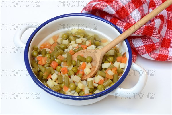 Ingredients for Russian salad in bowl and cooking spoon