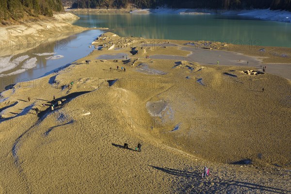 Deflated water reservoir with tourists in winter