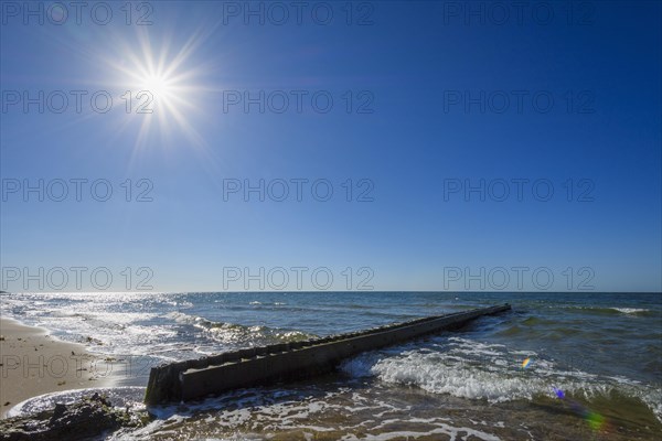 Wooden Breakwater on the Beach with Sun