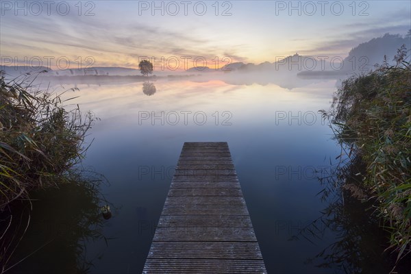 Wooden Jetty with Reflective Sky in Lake at Dawn