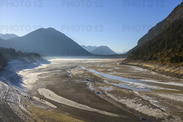 Deflated water reservoir with tourists in winter