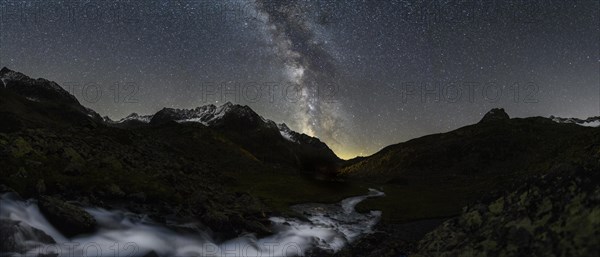 Mountain stream with Winnebachsee hut and Winnebach peaks with starry sky and Milky Way