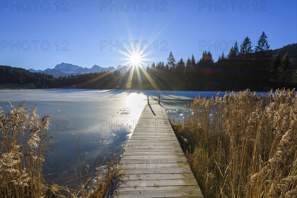 Wooden jetty with frozen lake and sun