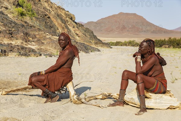 Himba women resting at the bank of the dry river bed of the Hoarusib river