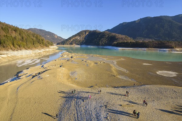 Deflated water reservoir with tourists in winter