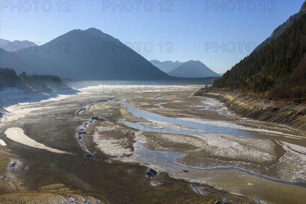 Deflated water reservoir with tourists in winter