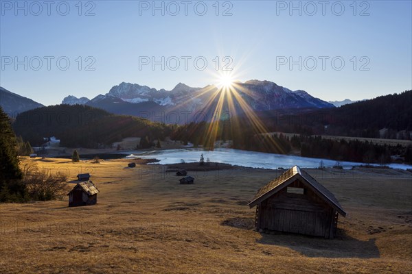 Sunrise over Karwendel mountain range with frozen lake and hay barn