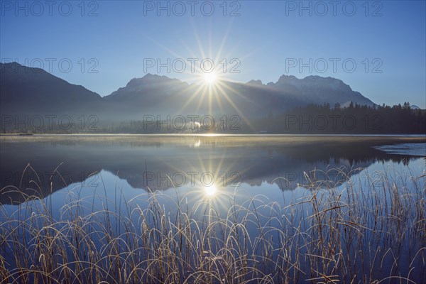 Lake Barmsee with reflected karwendel mountain range and sun