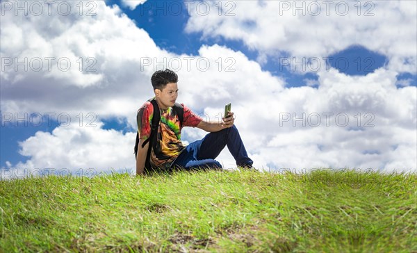 Backpacker with phone on top of a hill