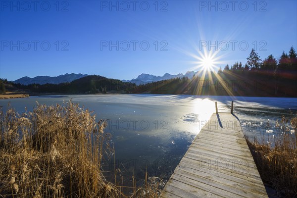 Wooden jetty with frozen lake and sun