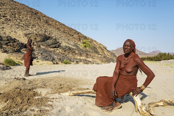 Himba women at the bank of the dry river bed of the Hoarusib river