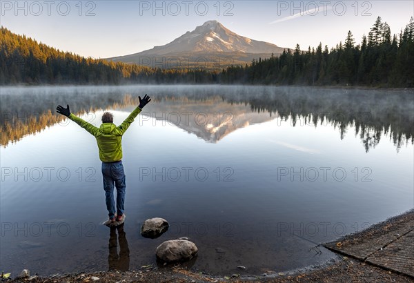 Young man standing on stone and stretching his arms in the air