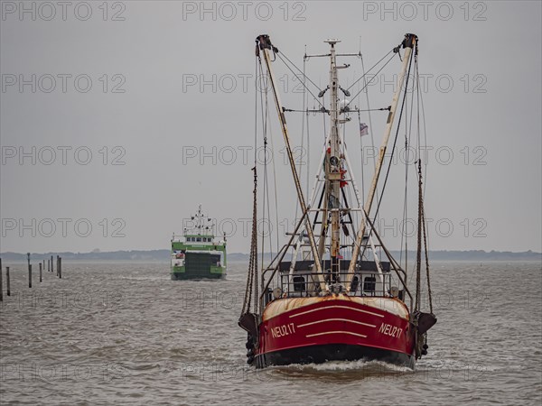 Crab cutter with ferry Spiekeroog IVon the stormy North Sea entering the harbour