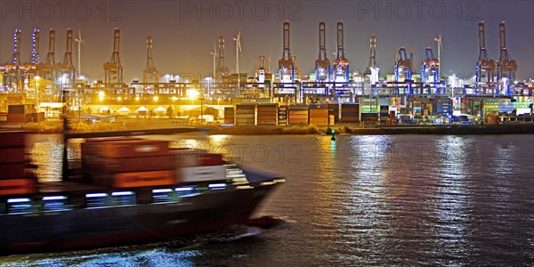 Container ship on the Norderelbe in front of loading cranes at the container terminal Burchardkai at night