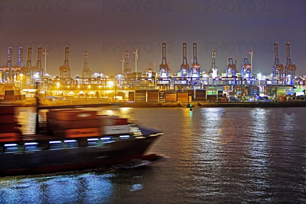 Container ship on the Norderelbe in front of loading cranes at the container terminal Burchardkai at night