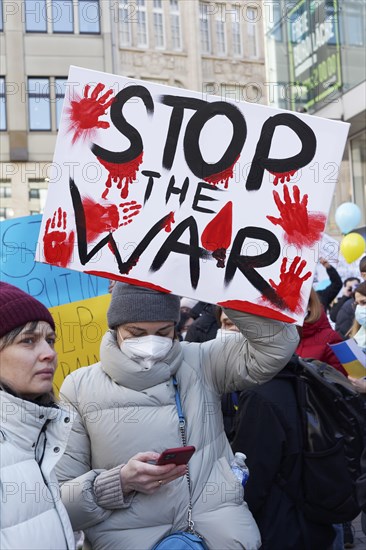 female protestor holds protest poster against the Russian invasion of Ukraine