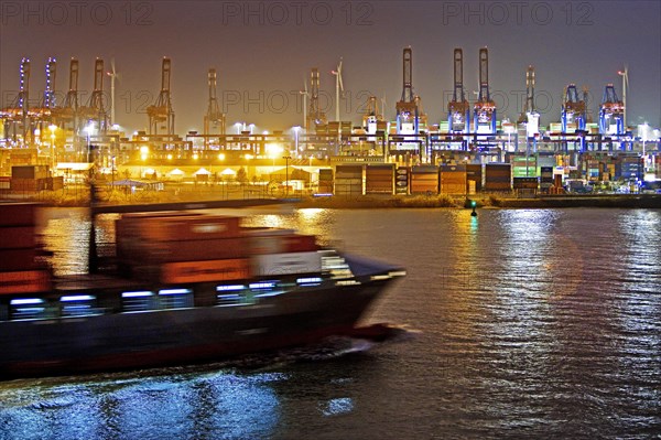 Container ship on the Norderelbe in front of loading cranes at the container terminal Burchardkai at night