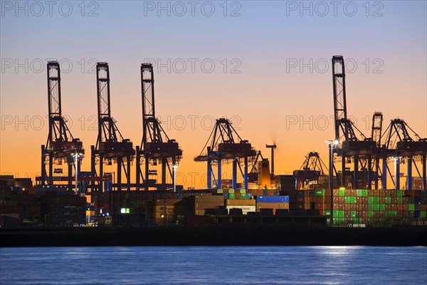 Loading cranes at the container terminal Burchardkai at sunset