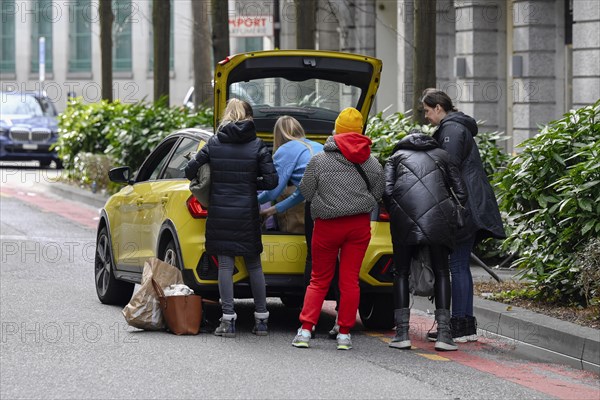 People stow luggage in the car trunk