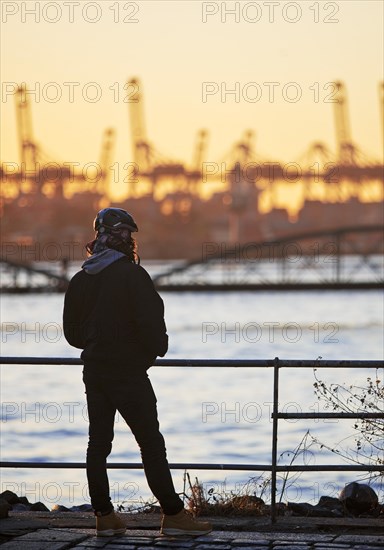 A person in front of loading cranes at the Norderelbe in Altona