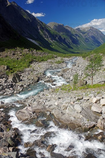 Wild stream in a narrow valley framed by mountains