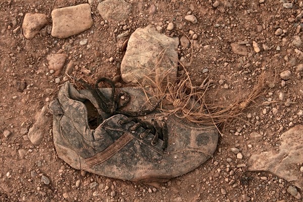 Ailing leather work boot stands on a wall