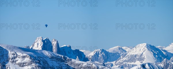 Hot air balloons flying over snow-covered Alpine peaks