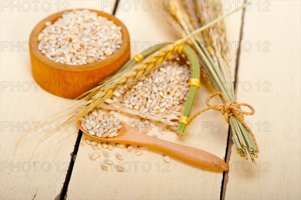 Organic barley grains over rustic wood table macro closeup