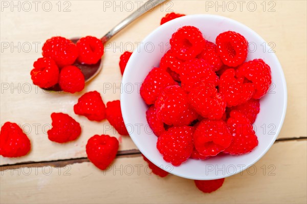 Bunch of fresh raspberry on a bowl and white wood rustic table