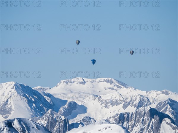 Hot air balloons flying over snow-covered Alpine peaks