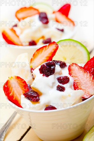 Fruit and yogurt salad healthy breakfast over white wood table