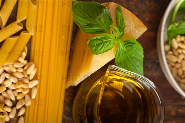 Italian basil pesto ingredients and raw pasta over old wood
