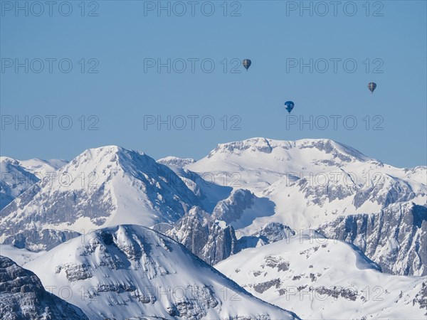 Hot air balloons flying over snow-covered Alpine peaks