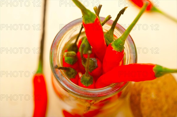 Red chili peppers on a glass jar over white wood rustic table