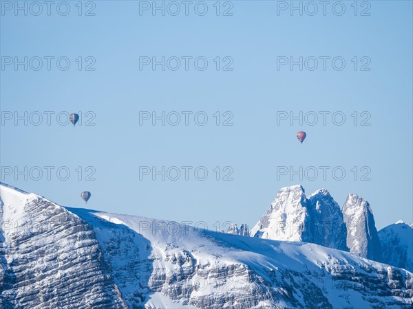 Hot air balloons flying over snow-covered Alpine peaks